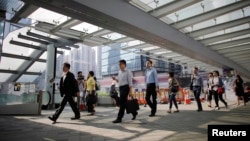 FILE - Government employees arrive to work at an area occupied by protesters outside of the government headquarters building in Hong Kong, Oct. 6, 2014. Chinese civil servants are experiencing pay cuts as the country recovers from COVID-related lockdowns. 