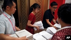 Workers prepare the China's national defense white paper to distribute to the reporters before a press conference at the State Council Information Office in Beijing, July 24, 2019. 