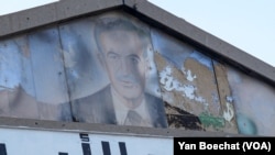 A picture of Hafez al-Assad, Syria's deceased dictator, next to the partial words 'Assad Forever' is seen outside an old Bath Party office in Damascus, Syria, on Dec. 10, 2024.