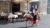 Seorang perempuan yang mengenakan masker, mengendarai sepeda di kota Roma, di tengah pandemi Covid-19 di Italia (25/10). 