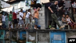 An agent (R) of Philippine Drug Enforcement Agency (PDEA) escorts suspects during a raid at an informal settlers' area inside a public cemetery in Manila on March 16, 2017.