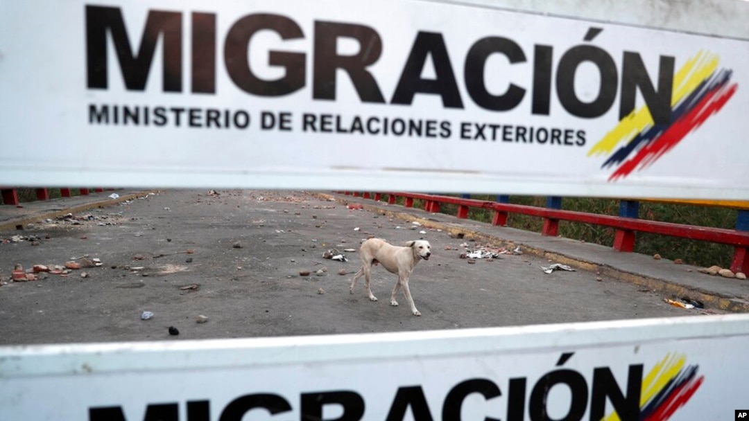 Un perro camina en el lado venezolano del Puente Internacional Francisco de Paula Santander, donde cuelgan carteles de migración en Ureña, Venezuela, el martes 26 de febrero de 2019, visto desde el otro lado del puente en Cúcuta, Colombia, mientras la frontera permanece cerrada.