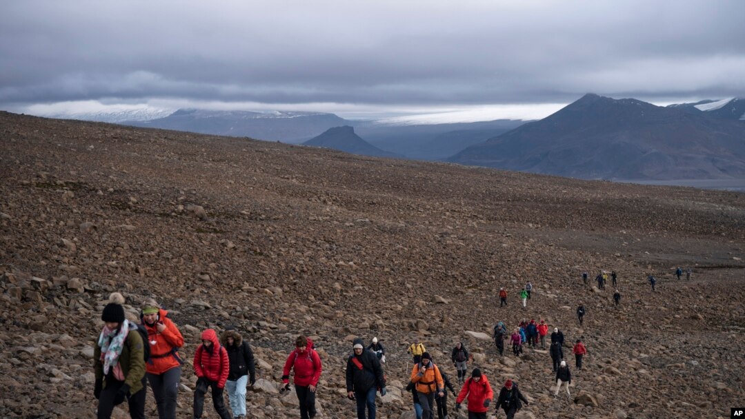 People climb to the top of what once was the Okjokull glacier, in Iceland, Aug. 18, 2019.