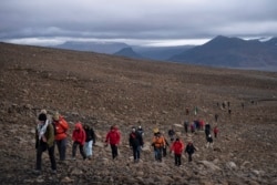 People climb to the top of what once was the Okjokull glacier, in Iceland, Aug. 18, 2019.