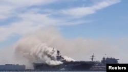 Un incendio en el buque de asalto anfibio de la Marina de los EE.UU. USS Bonhomme Richard en la Base Naval de San Diego, California, deja ver la nave rodeada por el humo en esta foto de redes sociales, el 12 de julio de 2020. [Foto: Charisma Emralino/via 