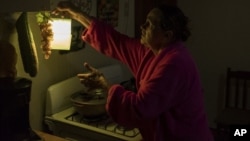 En esta imagen, tomada el 12 de julio de 2018, Marta Bermúdez Robles, de 66 años, cuelga una lámpara en su cocina, en Adjuntas, Puerto Rico, ante la falta de electricidad desde el paso de los huracanes Irma y María. 