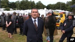 South western region sub prefect Laurent Nunez, center, manages riot policemen as they take up positions before closing a French itinerant peoples camp in Langlet, south western France, Friday Aug. 13, 2010. 