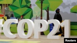 A woman walks past the COP21 logo in the Climate Generations area during the World Climate Change Conference 2015 (COP21) at Le Bourget, near Paris, France, Dec. 1, 2015. 