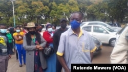 Zinbabweans wait in a long line to be vaccinated