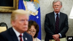 FILE - U.S. President Donald Trump, left, conducts a meeting in the Oval Office of the White House in Washington, May 22, 2018, as then-National Security Adviser John Bolton, right, looks on. 