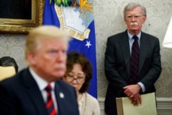 FILE - U.S. President Donald Trump, left, conducts a meeting in the Oval Office of the White House in Washington, May 22, 2018, as then-National Security Adviser John Bolton, right, looks on.