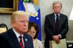 FILE - U.S. President Donald Trump, left, conducts a meeting in the Oval Office of the White House in Washington, May 22, 2018, as then-National Security Adviser John Bolton, right, looks on.