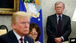 2018年5月22日，美国总统特朗普在白宫椭圆形办公室主持会议，时任国家安全顾问约翰·博尔顿（右）站在一旁。