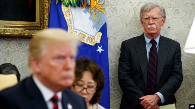 2018年5月22日，美国总统特朗普在白宫椭圆形办公室主持会议，时任国家安全顾问约翰·博尔顿（右）站在一旁。