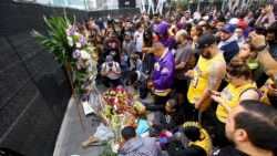 Fans of Kobe Bryant mourn at a memorial to him in front of Staples Center, home of the Los Angeles Lakers, after word of the Lakers star's death in a helicopter crash, in downtown Los Angeles, Jan. 26, 2020.