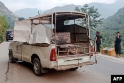 Petugas keamanan berdiri di dekat kendaraan polisi yang rusak di lokasi ledakan bom, di Malam Jabba di distrik Swat, provinsi Khyber Pakhtunkhwa, 22 September 2024. (Mehboob UL HAQ / AFP)