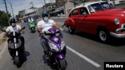 Motards transportant de la nourriture pour les personnes vulnérables dans le cadre des mesures prises par le gouvernement cubain pour lutter contre le COVID-19, La Havane, 1er avril 2020. (Reuters/Alexandre Meneghini)