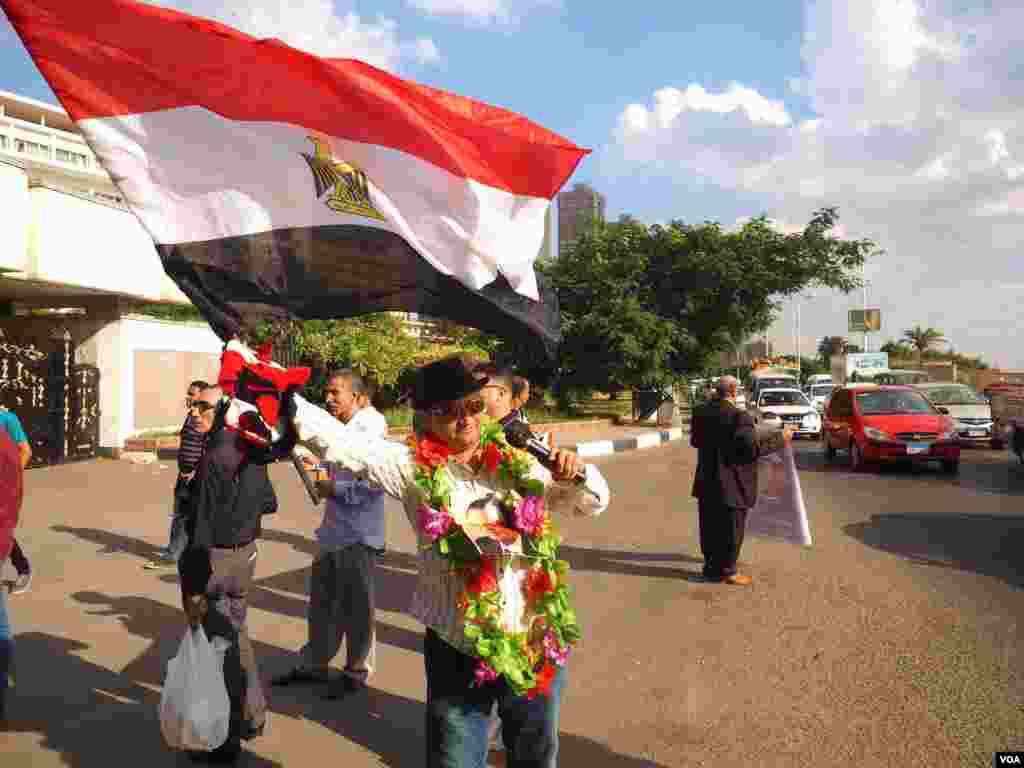 A Mubarak supporter waves the Egyptian flag outside Maadi Military hospital while the longtime ruler was recovering. Mubarak was repeatedly hospitalized for problems including heart trouble in his latter years. (Photo: Hamada Elrasam / VOA) 