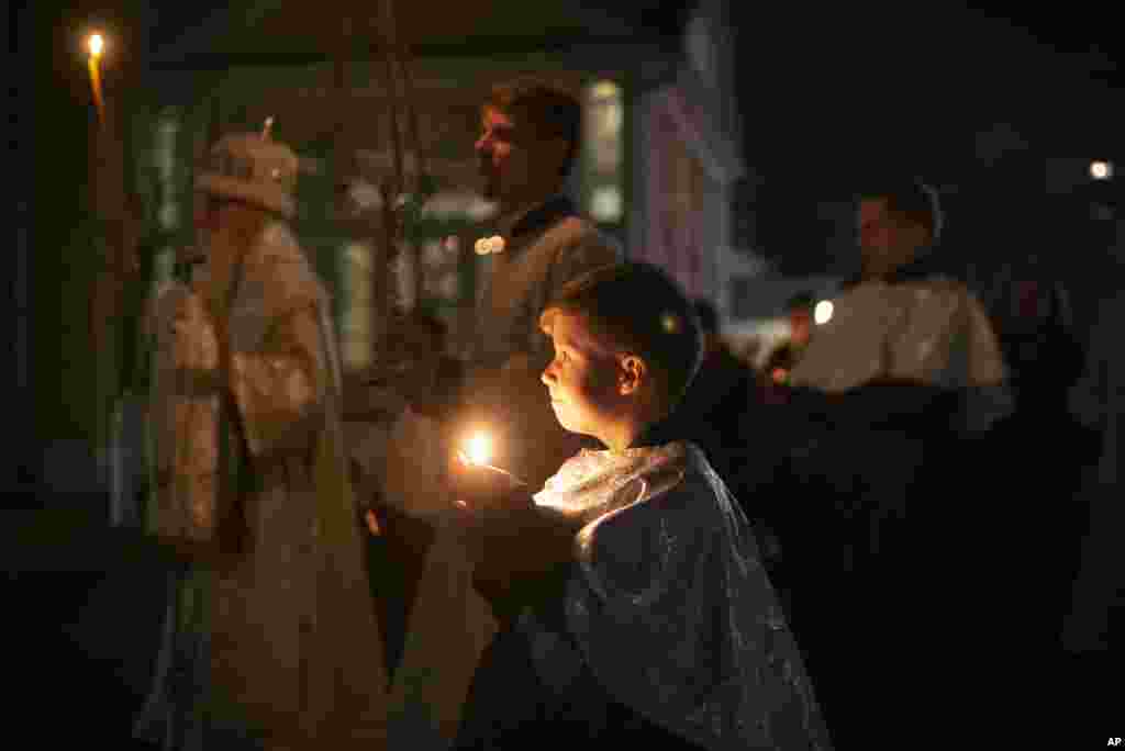 Un niño sostiene una vela en una procesión religiosa que celebra la Pascua ortodoxa en el centro espiritual Rogozhsky, de la Iglesia Ortodoxa Rusa de Rito Antiguo en Moscú, Rusia, el sábado 18 de abril de 2020.