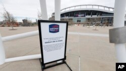 FILE - A "grounds closed" sign stands outside Empower Field at Mile High, the home of the NFL Denver Broncos, in Denver, April 30, 2020.