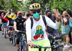 Activists ride their bicycles as they flash a three-finger salute of defiance during a rally called "Bike for Myanmar" against the military coup, in Jakarta, Indonesia, April 24, 2021.