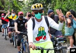 Activists ride their bicycles as they flash a three-finger salute of defiance during a rally called "Bike for Myanmar" against the military coup, in Jakarta, Indonesia, April 24, 2021.