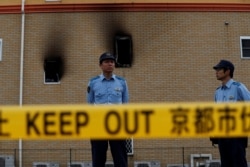 Policemen stand behind a police line at the torched Kyoto Animation building in Kyoto