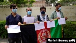 Warga Afghanistan yang belajar di India memegang plakat dan berdiri di luar Kedutaan Besar AS meminta bantuan, di New Delhi, India, Sabtu, 28 Agustus 2021. (Foto: AP/Manish Swarup)