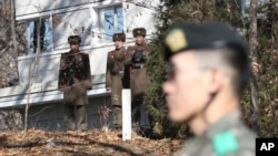  In this Nov. 27, 2017, file photo, North Korean soldiers look at the South side as a South Korean stands guard near the spot where a North Korean soldier crossed the border on Nov. 13 at the Panmunjom, in the Demilitarized Zone, South Korea.