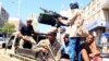 FILE - Government soldiers ride on the back of a patrol truck on a street where people demonstrated against the deterioration of Yemen's economy and the devaluation of the local currency.