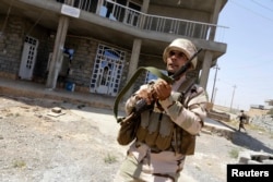 FILE - A Kurdish Peshmerga fighter runs as he and comrades sweep the Bakirta village after Islamic State insurgents withdrew from the town, near Makhmur, south of Irbil, the capital of Iraqi Kurdistan, Aug. 27, 2014.