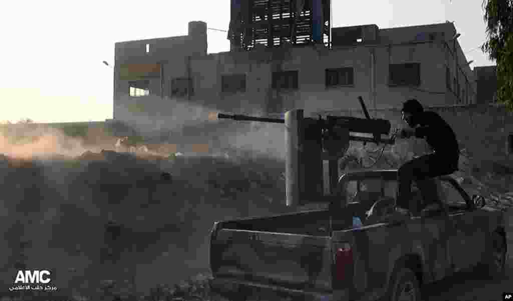 This citizen journalism image provided by Aleppo Media Center shows a Syrian rebel firing a weapon towards Syrian government troops loyal to President Bashar Assad in Aleppo, Nov. 9, 2013.