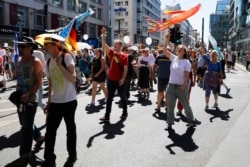 People - mostly without face masks - attend a demonstration against coronavirus restrictions in Berlin, Aug. 1, 2020.