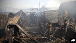 Men take photos of the ruins left after a fire devastated an electronic appliances market in Kabul, Afghanistan, Nov. 2, 2018. Residents of the Afghan capital are grappling with the aftermath of a massive blaze that destroyed hundreds of stores at a market in Kabul.