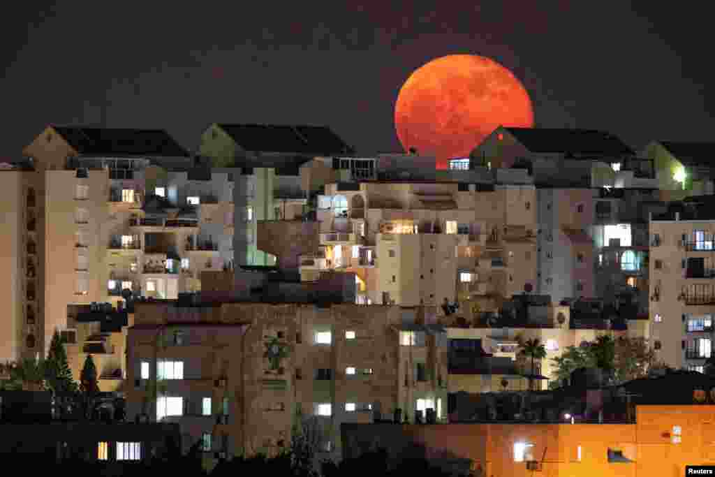 A full moon can be seen behind buildings at night in Ashkelon, Israel, Dec. 1, 2020.