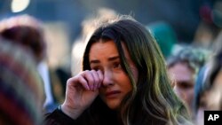 FILE -A mourner wipes a tear during a vigil honoring students killed and injured in shootings at Michigan State University in East Lansing, Mich., Feb. 15, 2023. 