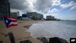 Bendera Puerto Rican berkibar di tepi pantai yang sepi di Ocean Park, San Juan, Puerto Rico, 21 Mei 2020. 