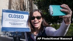 Jamie Parrish, asal Minneapolis, berswafoto di depan tanda yang berbunyi tidak beroperasinya Arsip Nasional pada tanggal 22 Desember 2018 di Washington, D.C. (foto: AP Photo/Alex Brandon)