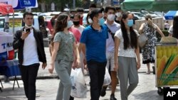 Youths in face masks walk through a street market in Bishkek, Kyrgyzstan, July 24, 2020, as coronavirus cases surged there after authorities lifted a tight lockdown in May, overwhelming the health care system.