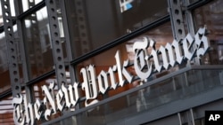 FILE - In this Thursday, May 6, 2021, photo, a sign for The New York Times hangs above the entrance to its building, in New York.