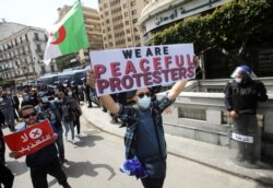 FILE - Demonstrators march with banners and flags during a protest demanding political change, in Algiers, Algeria, April 9, 2021.