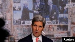 U.S. Secretary of State John Kerry stands in front of photo (L-R) showing Jordan's former King Hussein, former U.S. President Bill Clinton and Israel's former Prime Minister Yitzhak Rabin, as Kerry marks 18th anniversary of Rabin's assassination, in Tel Aviv, Nov. 5, 2013.