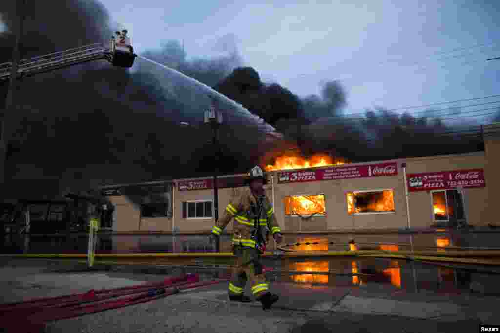 Petugas pemadam kebakaran New Jersey menyemprotkan air ke bangunan yang terbakar untuk mengendalikan kebakaran besar di Seaside Park di New Jersey, Amerika. Api melalap beberapa blok kawasan bisnis di Seaside Park, kota pantai yang sedang dalam pembangunan kembali dari kerusakan yang disebabkan oleh badai Sandy. 