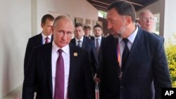 Presiden Rusia Vladimir Putin (kiri) berbincang dengan penguasaha aluminium Rusia, Oleg Deripaska.