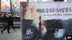 Poster na ulici Seula na kojem se vide izgladnela severno korejska deca i raketa, 24. januar, 2013.