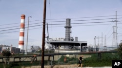 A jogger runs past the Scattergood power plant, Feb. 12, 2019, in Los Angeles. Los Angeles will abandon a plan to spend billions rebuilding three natural gas power plants as the city moves toward renewable energy, Mayor Eric Garcetti said Monday.