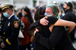 Stephanie Jayne, right, hugs a friend at a vigil at City Hall in San Jose, Calif., May 27, 2021, in honor of the multiple people killed when a gunman opened fire at a rail yard the day before.