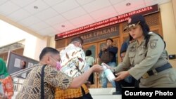 Warga yang mengurus administrasi kependudukan diminta mencuci tangan dengan hand sanitizer yang disediakan Pemkot Solo, Senin, 16 Maret 2020. (Foto: Humas Pemkot Surakarta)