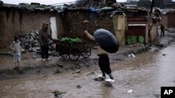 FILE - Pakistani man crossing flooded path during heavy rain fall in slum on outskirts of Islamabad, Pakistan. 