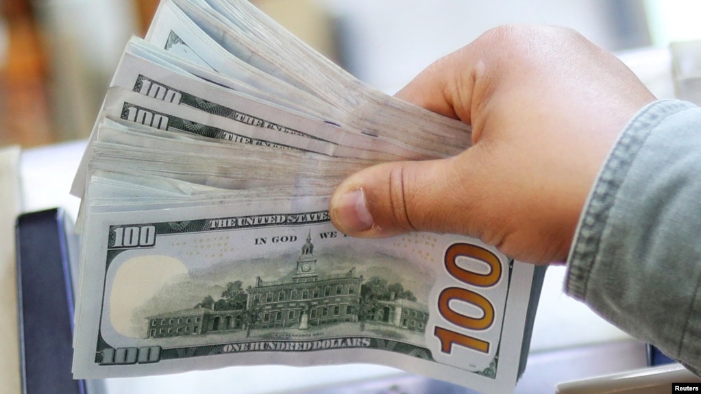 资料照：一人手拿一叠百元美钞。(photo:VOA)
